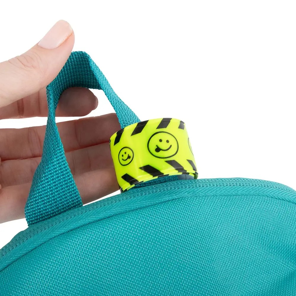 Close-up of reflective snap wristband wrapped around a backpack handle, fluorescent yellow band with smiley pattern improving visibility for kids and daily use