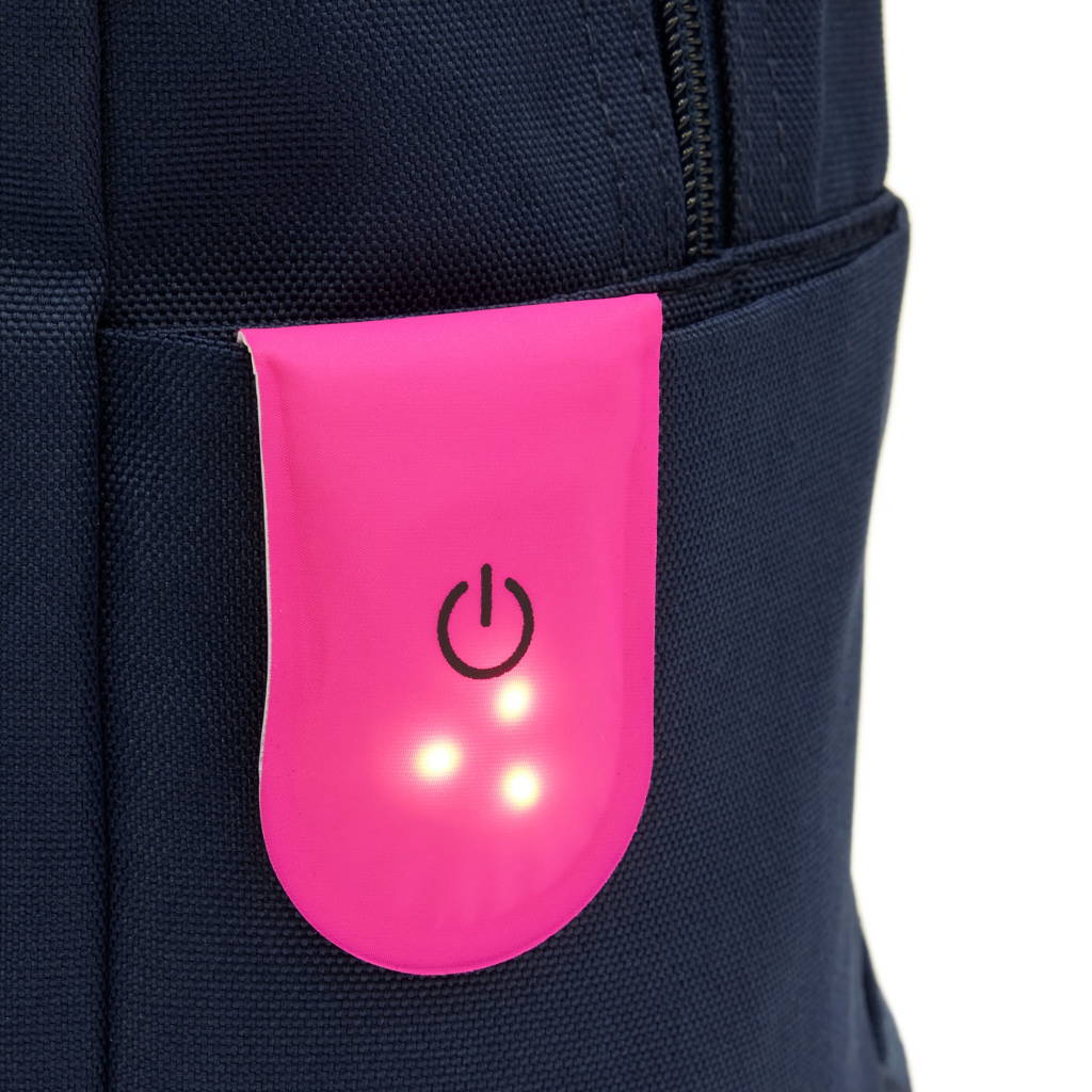 Pink LED magnetic light clip attached to a backpack pocket, showing bright LED lights for improved visibility and safety