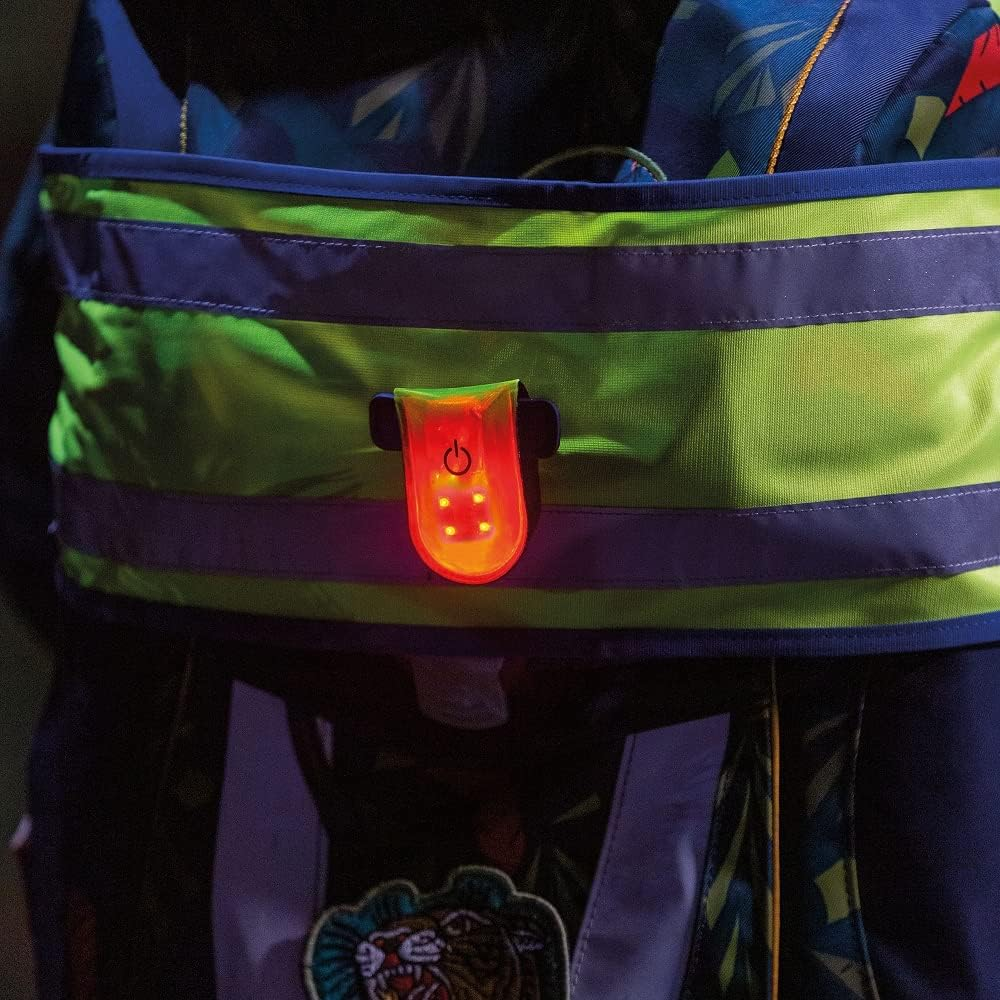 Red LED magnetic clip safety light attached to reflective backpack strap at night for enhanced visibility