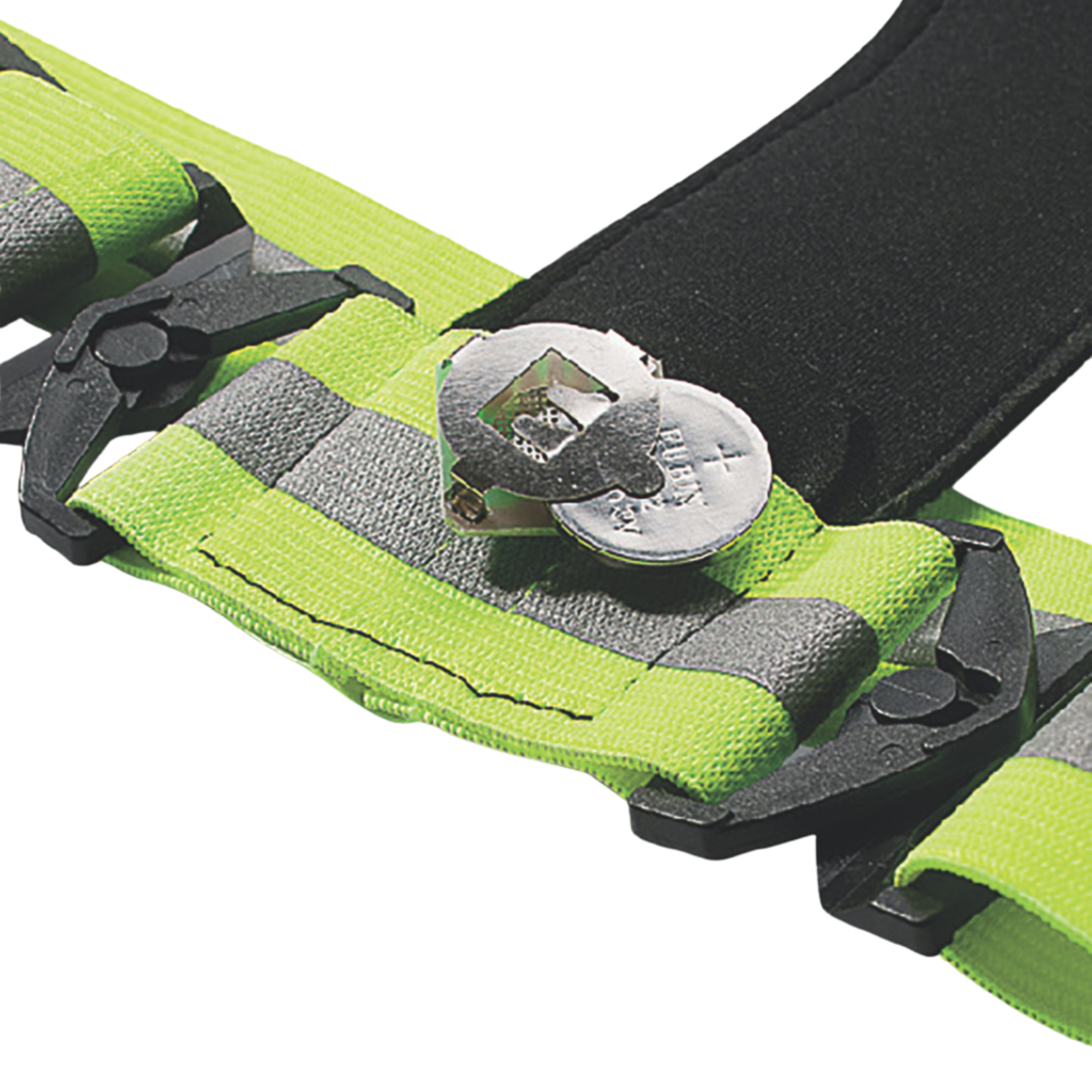 Close-up detail of LED reflective running harness showing CR2032 replaceable button battery compartment, reflective elastic strap and secure buckle design